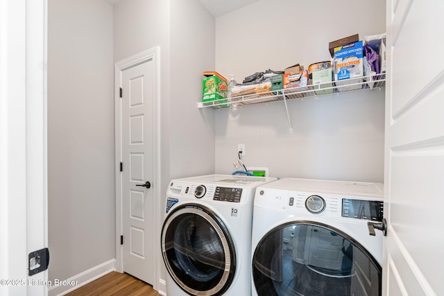 washroom with laundry area, wood finished floors, washing machine and dryer, and baseboards