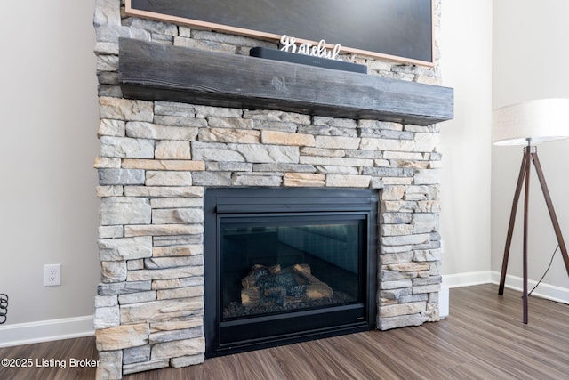 interior details featuring baseboards, wood finished floors, and a stone fireplace