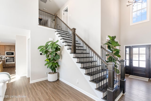 foyer entrance featuring stairs, a high ceiling, baseboards, and wood finished floors