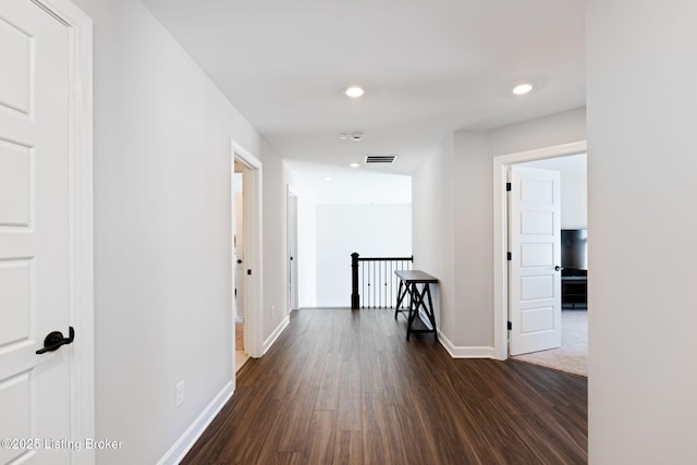 hallway featuring recessed lighting, baseboards, dark wood-type flooring, and an upstairs landing