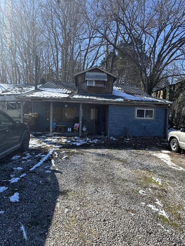 view of front of property featuring driveway, a porch, and metal roof