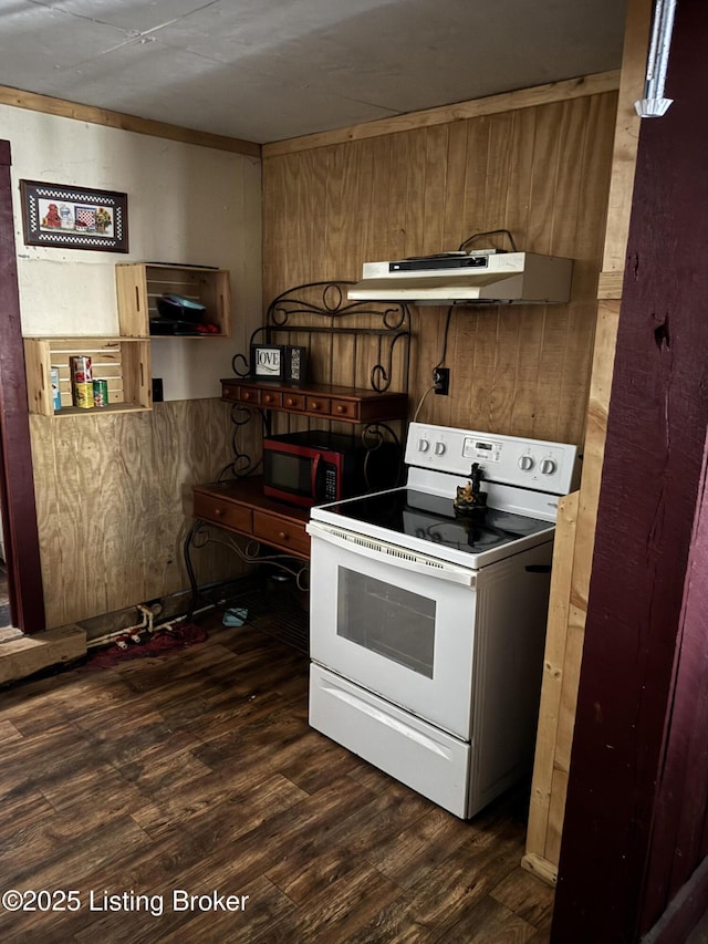 kitchen with dark wood-type flooring, wood walls, under cabinet range hood, and white range with electric cooktop