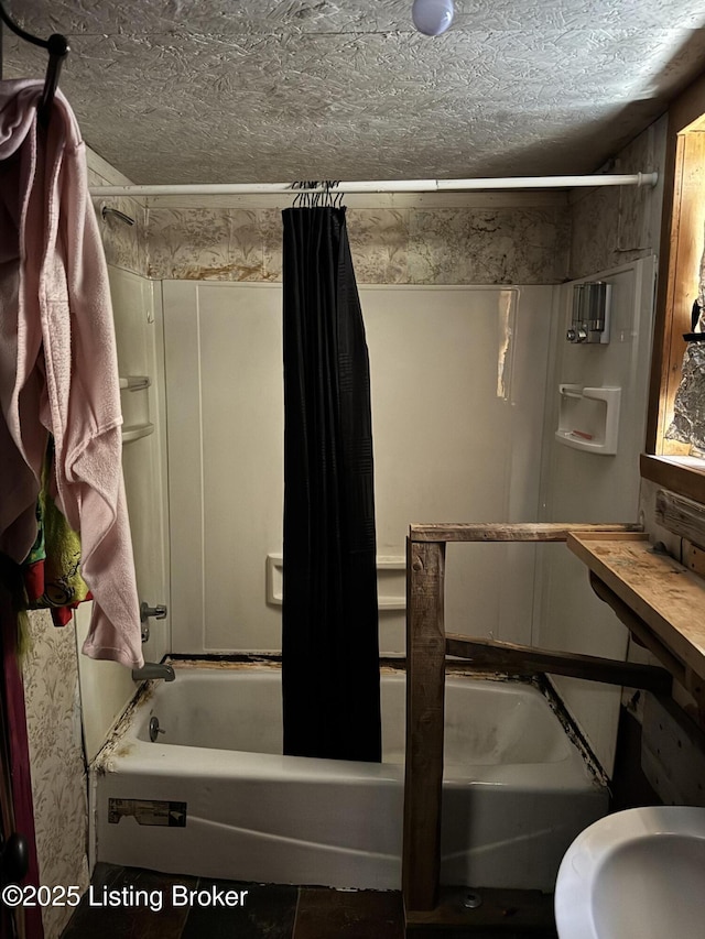 bathroom with a textured ceiling and shower / tub combo with curtain