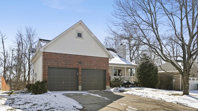 view of front of property with a garage, brick siding, a chimney, and a porch