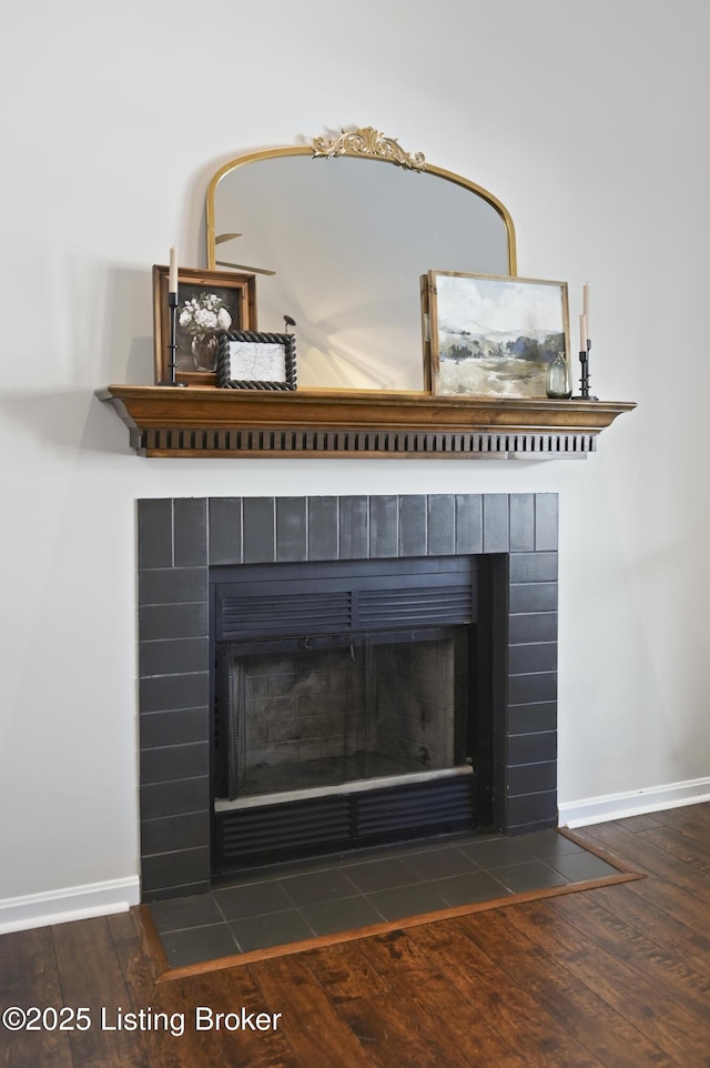 room details featuring a fireplace, baseboards, and wood finished floors