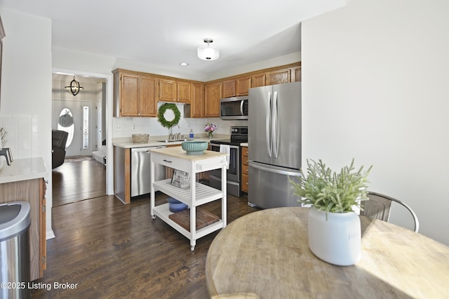 kitchen with dark wood-style floors, brown cabinets, stainless steel appliances, light countertops, and a sink