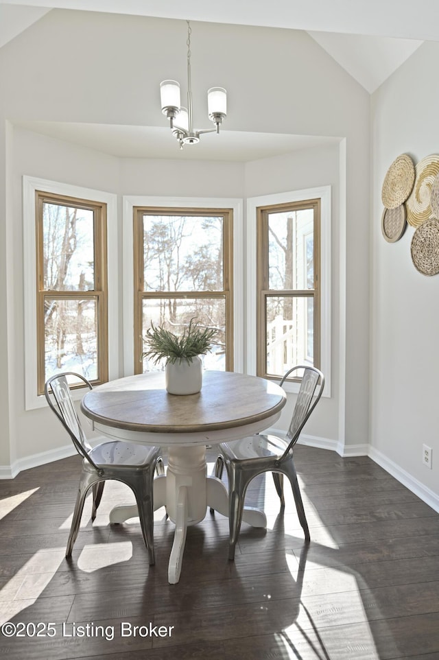 dining room with lofted ceiling, dark wood-type flooring, plenty of natural light, and an inviting chandelier