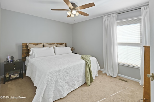 carpeted bedroom with a ceiling fan, visible vents, and baseboards