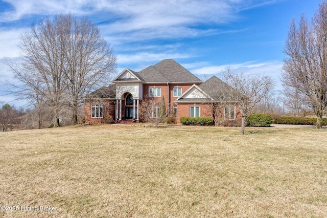 view of front of home with brick siding, a front yard, and a shingled roof