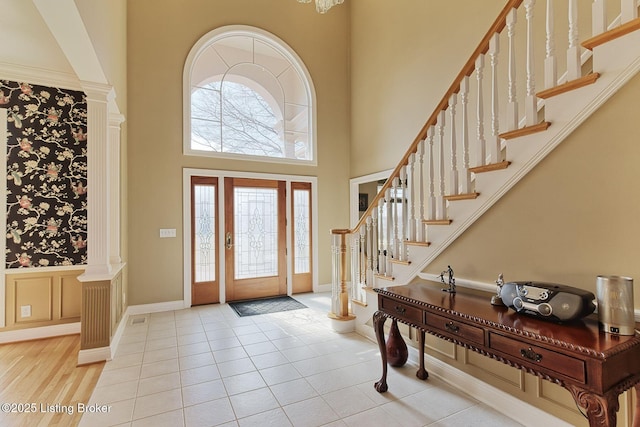 foyer entrance featuring stairs, a high ceiling, baseboards, and light tile patterned flooring