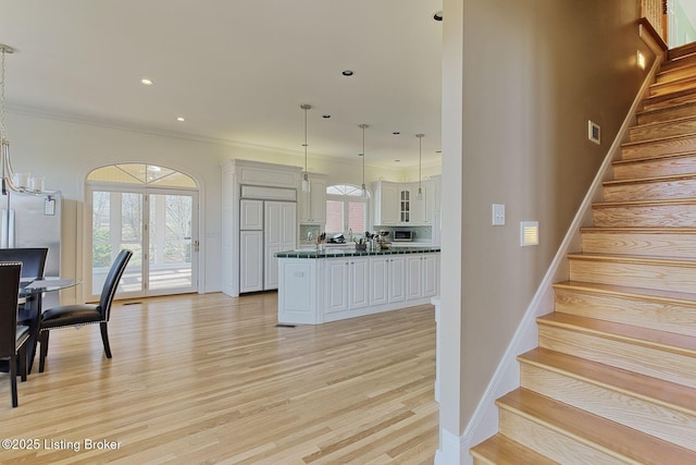 kitchen featuring visible vents, white cabinets, dark countertops, decorative light fixtures, and light wood-type flooring