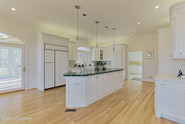 kitchen with tasteful backsplash, visible vents, light wood-style floors, and crown molding