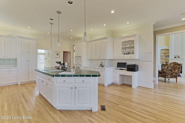 kitchen featuring tile countertops, a center island, white cabinetry, and light wood-style floors