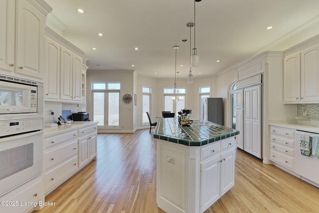 kitchen featuring a kitchen island, tile counters, ornamental molding, and built in appliances