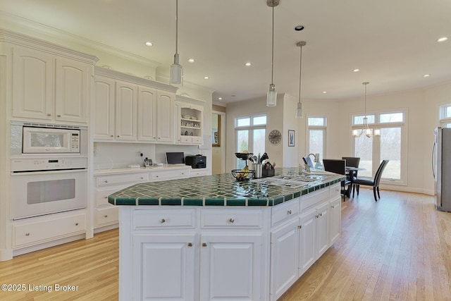 kitchen with tile counters, a center island, white appliances, and crown molding