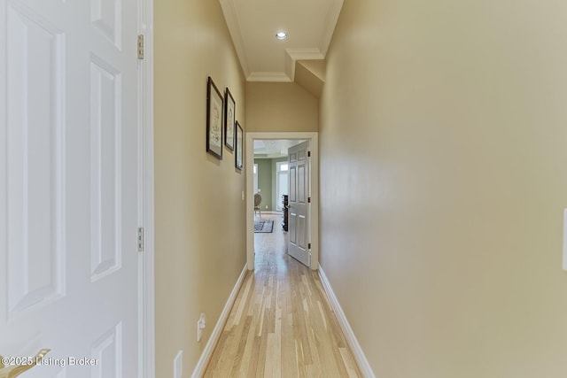 hall featuring crown molding, light wood-type flooring, and baseboards