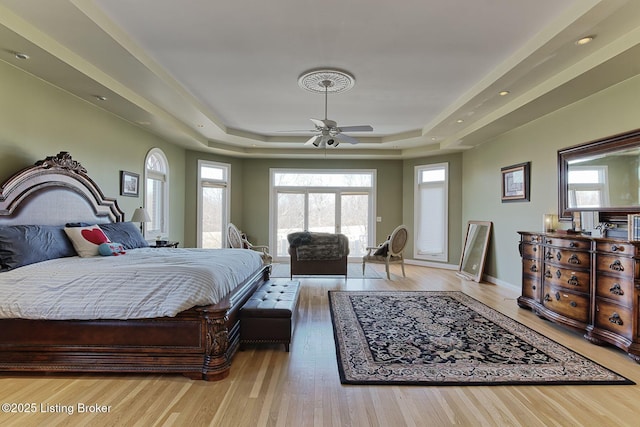 bedroom featuring a tray ceiling, baseboards, and wood finished floors