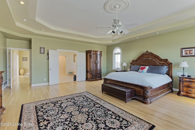 bedroom with ceiling fan, recessed lighting, baseboards, light wood-style floors, and a tray ceiling