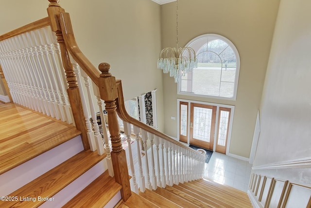 stairway featuring baseboards, a notable chandelier, and a high ceiling