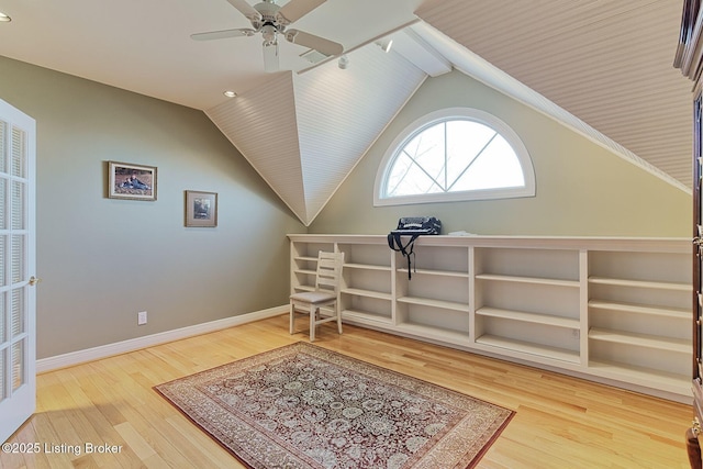 living area featuring lofted ceiling, ceiling fan, baseboards, and wood finished floors