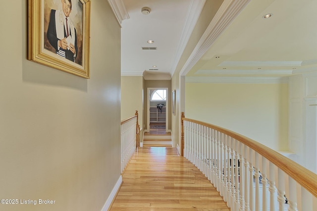 hallway featuring light wood finished floors, recessed lighting, visible vents, and ornamental molding