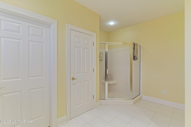 full bathroom with a stall shower, tile patterned flooring, and baseboards