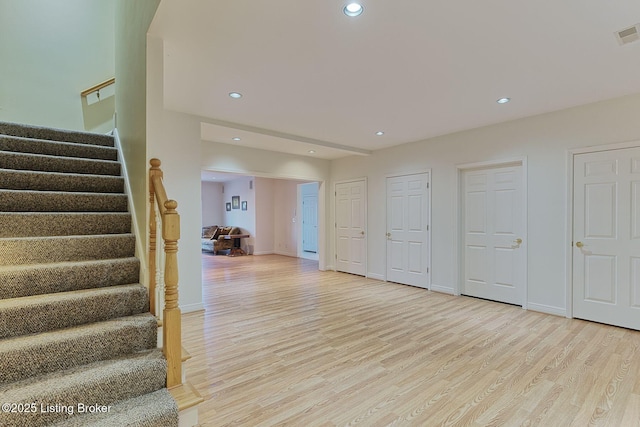 interior space featuring recessed lighting, baseboards, stairway, and light wood finished floors