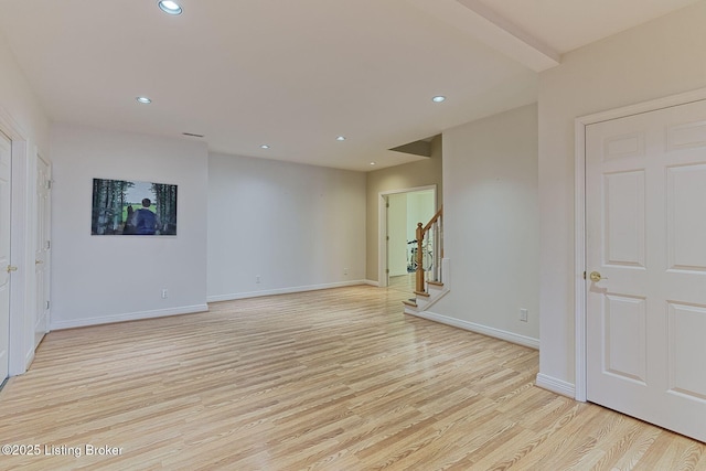 empty room featuring light wood-type flooring, baseboards, stairway, and recessed lighting