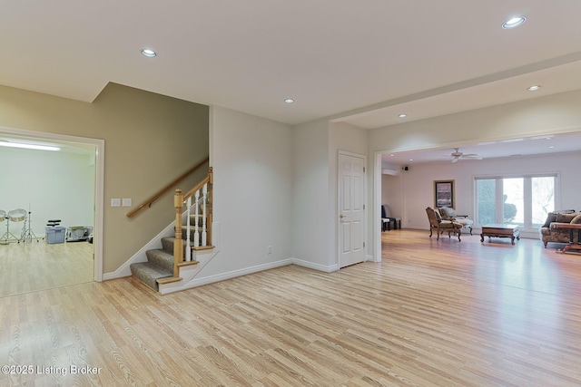 spare room with recessed lighting, baseboards, light wood finished floors, and stairs