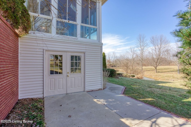 property entrance featuring a patio area and a lawn