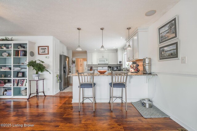950 Lakeview Dr, Bloomfield, KY 40008 - kitchen with wood finished floors, a peninsula, stainless steel fridge with ice dispenser, light stone countertops, and white microwave