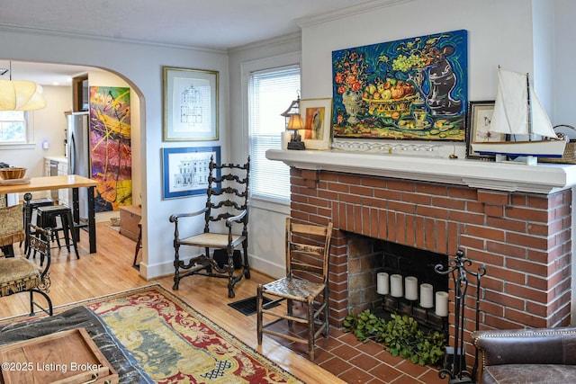 living area featuring arched walkways, ornamental molding, a fireplace, and a healthy amount of sunlight