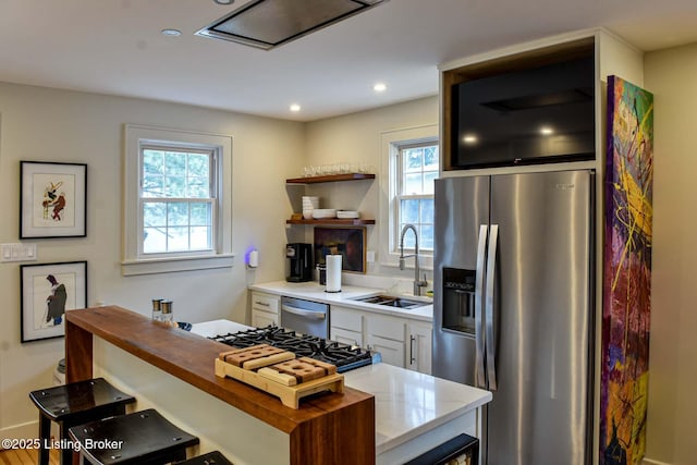 kitchen featuring recessed lighting, stainless steel appliances, a sink, wood counters, and white cabinets