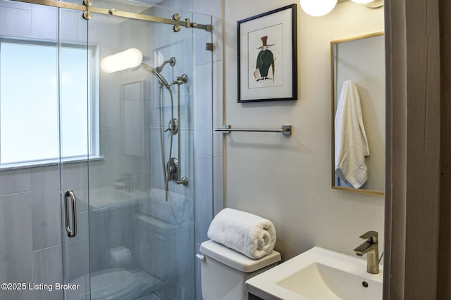 bathroom with toilet, a stall shower, and a sink