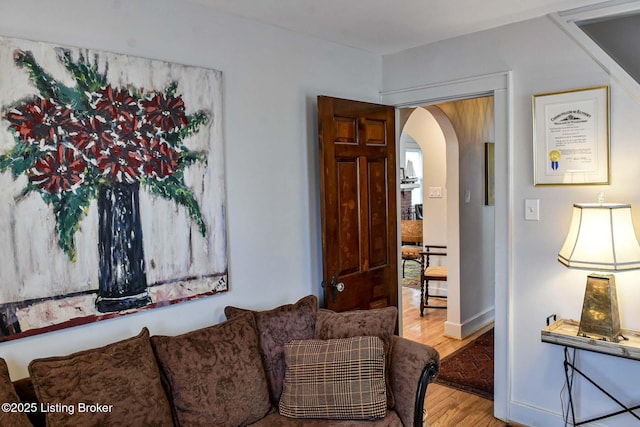 living room with baseboards, arched walkways, and wood finished floors