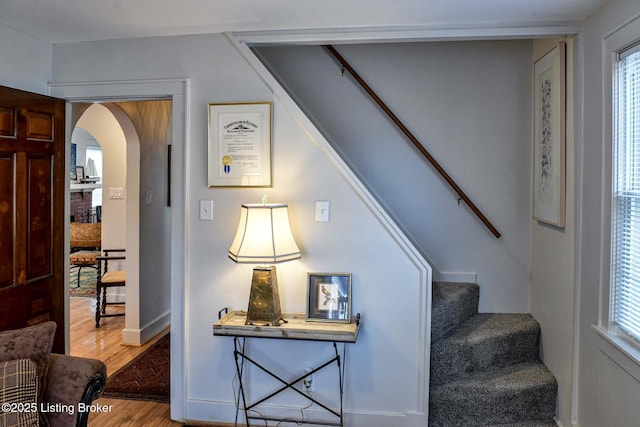 staircase with arched walkways and wood finished floors