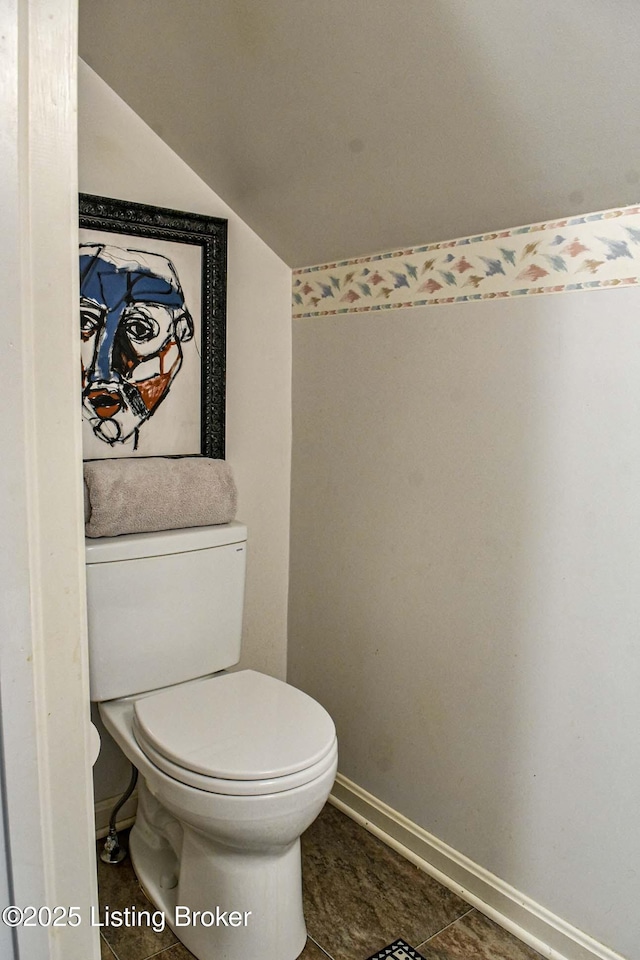 bathroom with vaulted ceiling, toilet, and baseboards