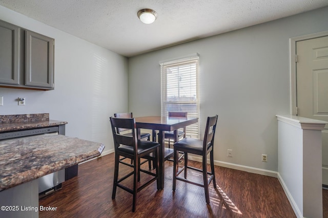 dining room featuring baseboards, dark wood finished floors, and a textured ceiling