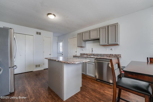 kitchen with appliances with stainless steel finishes, gray cabinets, visible vents, and a sink