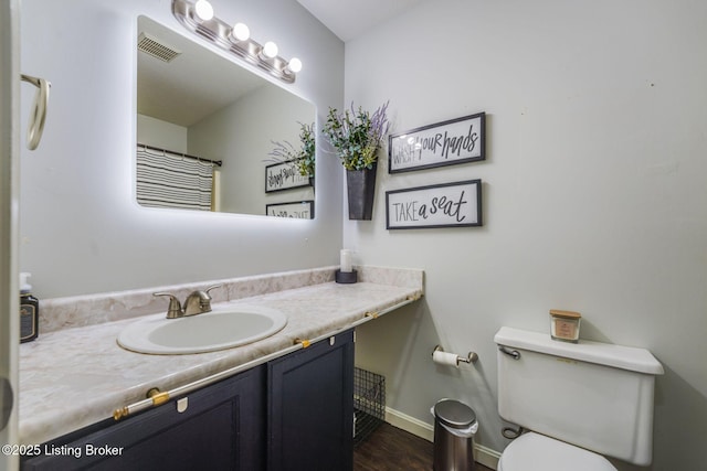 bathroom with baseboards, visible vents, toilet, wood finished floors, and vanity