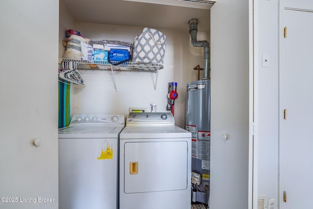 clothes washing area featuring laundry area, water heater, and washer and clothes dryer