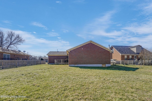 rear view of property with a fenced backyard, a lawn, and brick siding