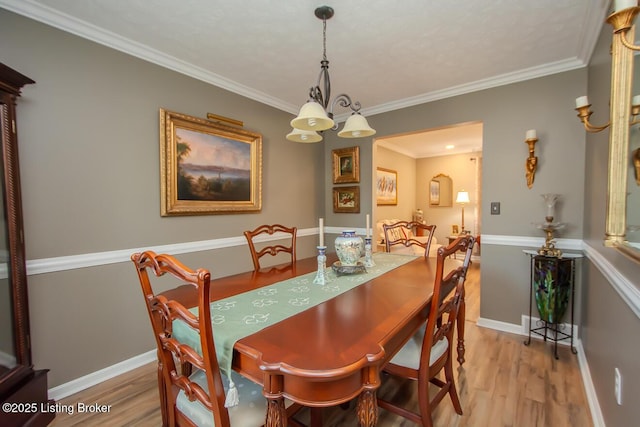 dining room with light wood finished floors, baseboards, and crown molding