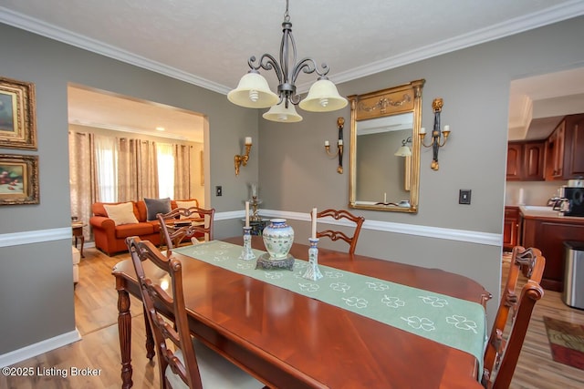 dining room with ornamental molding, a chandelier, baseboards, and light wood finished floors