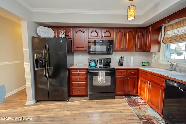 kitchen featuring ornamental molding, light countertops, light wood-type flooring, black appliances, and a sink