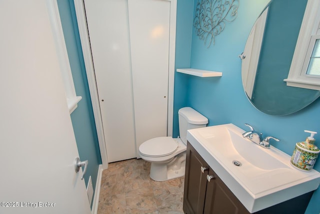 bathroom with toilet, stone finish floor, and vanity