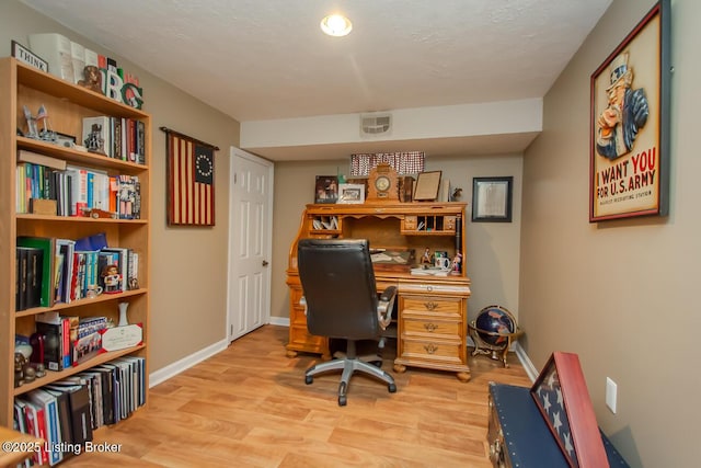 home office featuring light wood-type flooring, visible vents, and baseboards