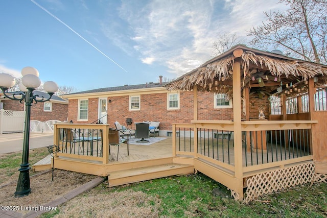 rear view of property featuring a wooden deck, fence, and brick siding