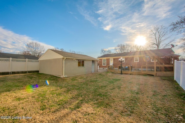 rear view of property featuring fence, an outdoor structure, a lawn, and a wooden deck