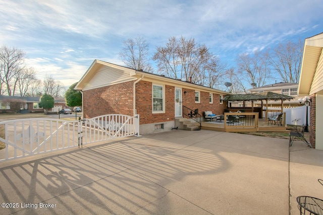 back of property featuring entry steps, a gate, fence, a deck, and brick siding